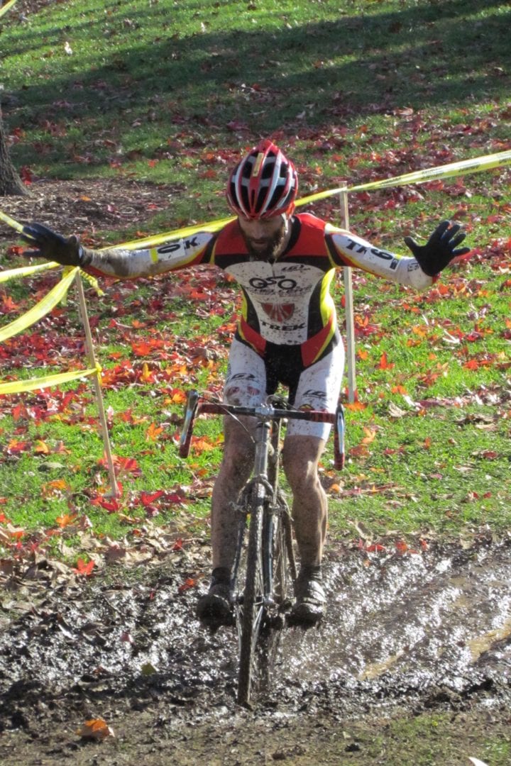 A cyclist doing no-hands over a muddy path